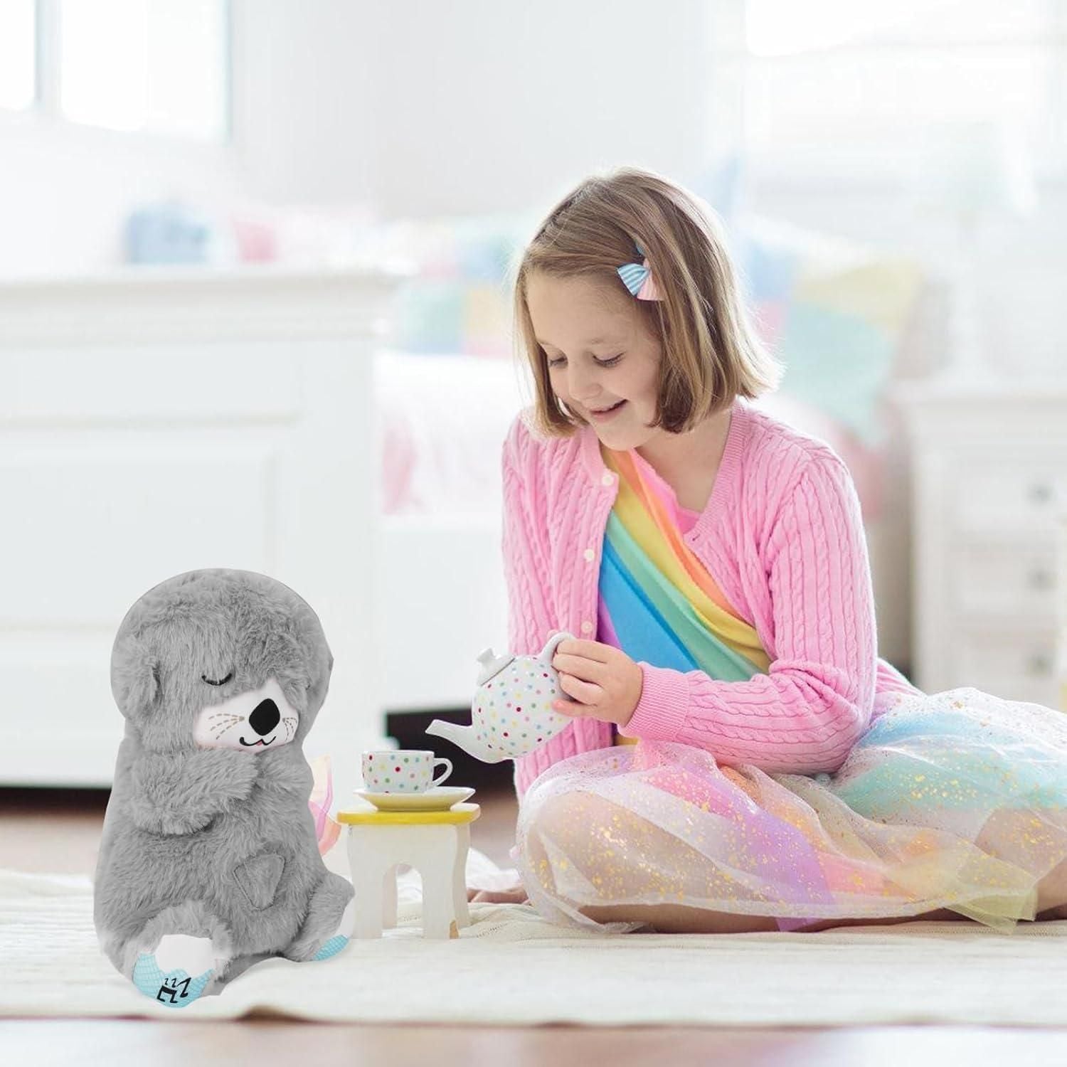 Young girl in a colorful dress and pink cardigan playing with a plush toy on a light-colored floor.