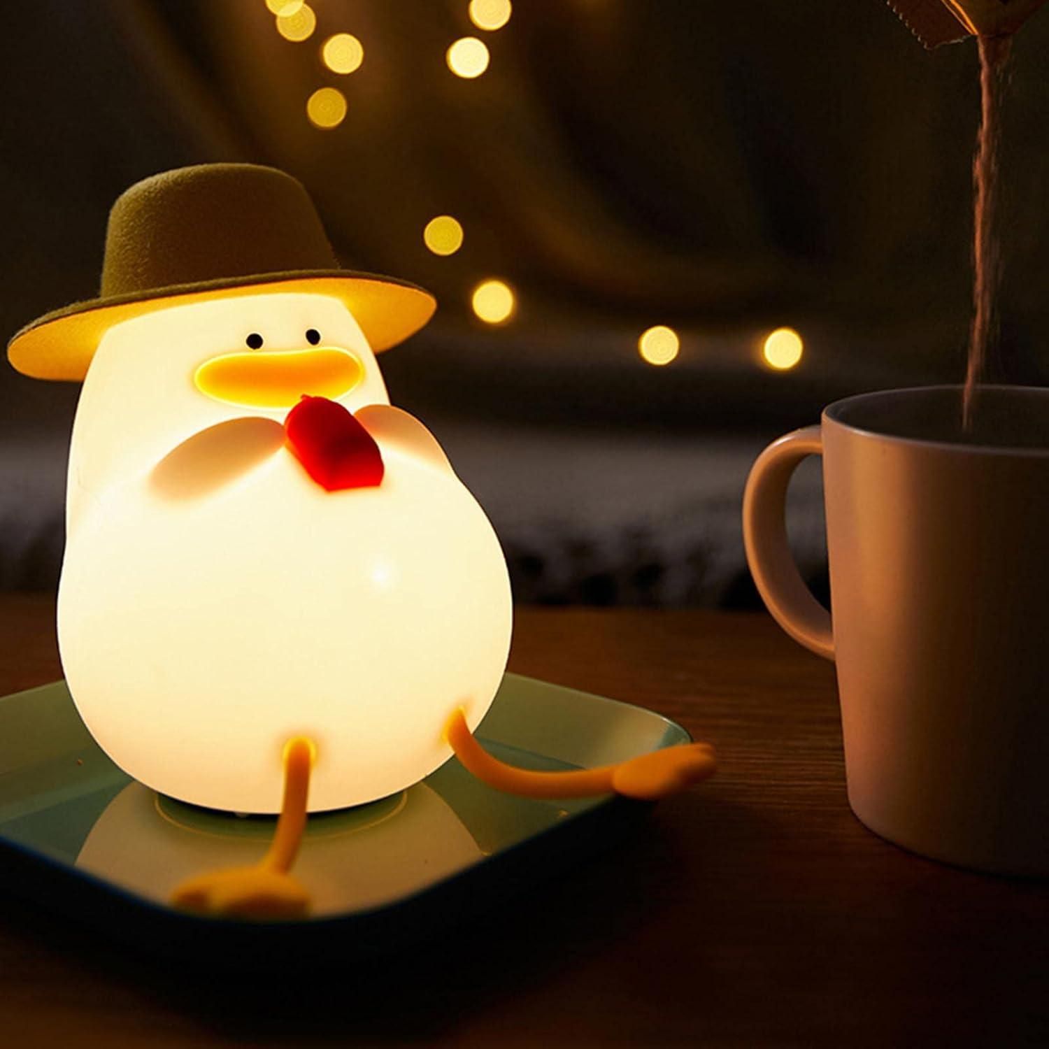 Light-up penguin figurine with a hat and scarf on a table next to a mug, with warm string lights in the background.